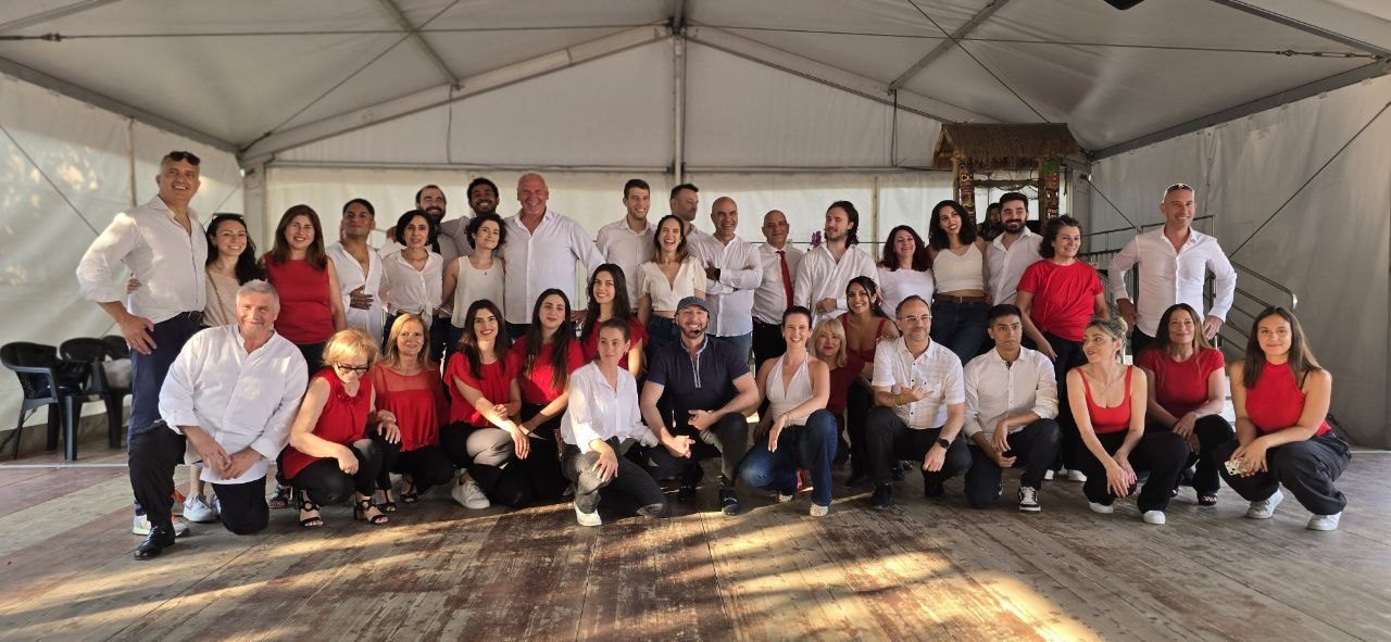 Foto di gruppo di una quarantina di persone, in bianco e rosso, sulla pista di una trasferta