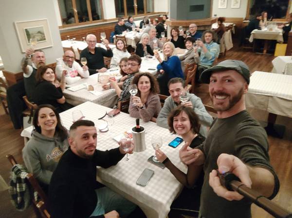 Il gruppo della scuola a cena durante il weekend fuori, tutti che brindano verso la macchina fotografica