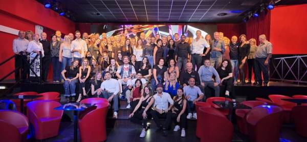 Foto di gruppo della scuola dentro un locale, con le poltroncine rosse e le luci colorate